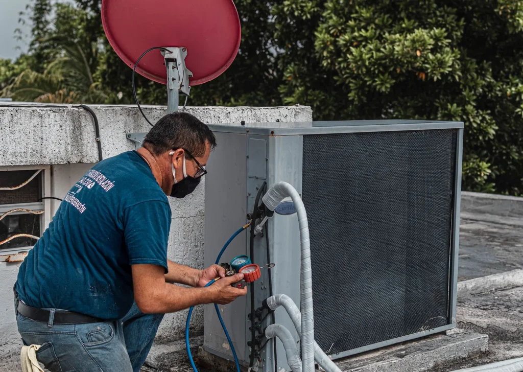 Technician connecting manifold gauges to an outdoor AC unit during a gas top-up
