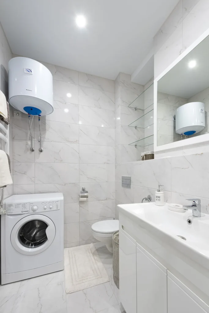 Wall-mounted geyser installed above a bathroom washing machine
